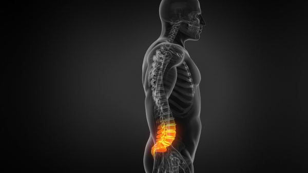 Imaging scan of a man's bones, trunk, and head viewed from the side on a dark background; orangey-red color on lower spine suggests low back pain 